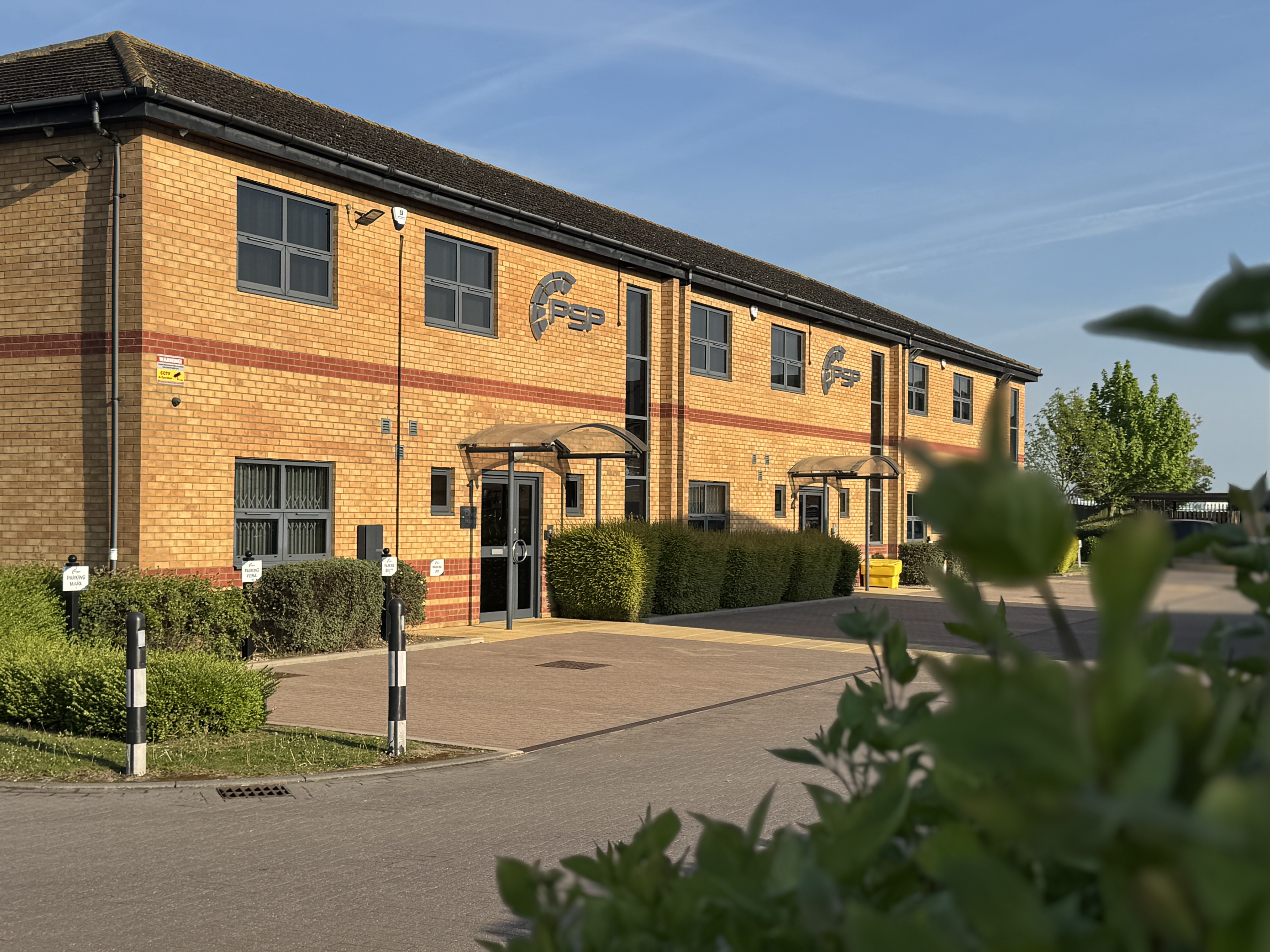 PSP offices in the morning sun with an empty car park overlooked from some bushes